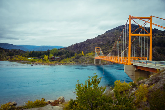 Red suspension bridge over the water runoff of General Carrera Lake, near Lake Bertrand, Puerto Tranquilo, Chile Chico, Aysen, Chile, Patagonia