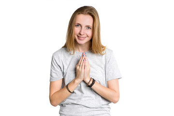 Portrait of a young woman who is holding her hands in front of her in greeting, meditation or prayer isolated on a white background.