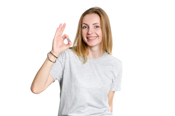 Portrait of a young woman who shows fingers a percent sign or an OK symbol on a white background. Pointing hand the number 0.