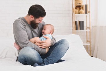 Bearded father trying to calm down newborn baby