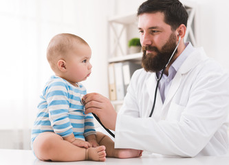 Pediatrician listening to kid's chest checking heartbeat