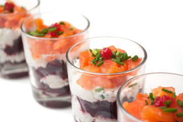 closeup of beet and salmon appetizers in little glasses on white background