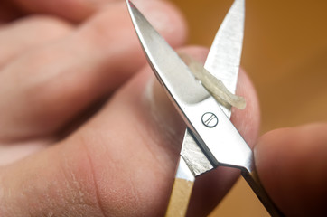 Man cuts toenails with scissors, close-up
