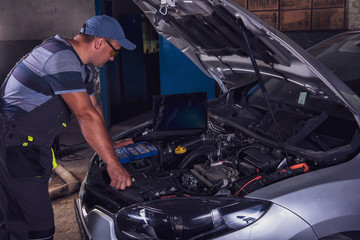Car service worker diagnoses car breakdown.