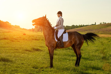 Young woman riding a horse on the green field