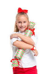 Full length portrait of cute little kid girl in stylish clothes looking at camera and smiling, standing against white studio wall with big candy . Kids fashion concept