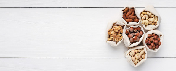 Various nuts in burlap bags on wooden background