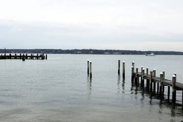 Coastal harbor with wooden pier dock on sandy rocky beach