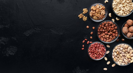 Various nuts in glass bowls on black background