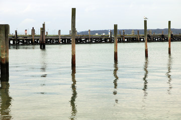 Coastal harbor with wooden pier dock on sandy rocky beach