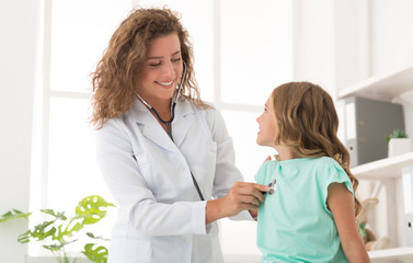 Woman pediatrician examining girl in office in clinic