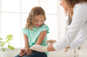 Frightened girl receiving injection in doctor's office