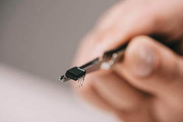 cropped view of tweezers with microchip hand of man on grey background