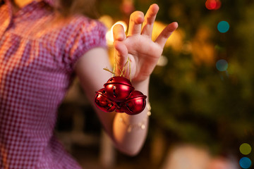 Three little red jingle bells in the hand of child - obrazy, fototapety, plakaty