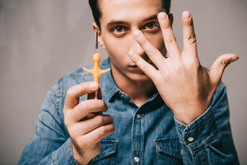 handsome man showing hand and holding syringe for microchipping on grey background