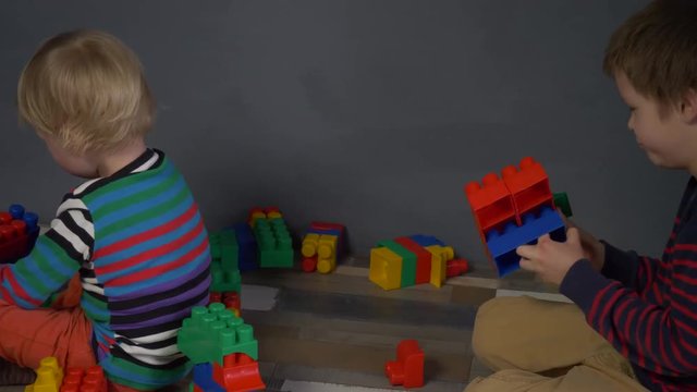 Cute children preschoolers play in color cubes, blocks. Boys are actively building new forms and expressing their emotions. Brothers study and get ready for school. Kids are happy to play together