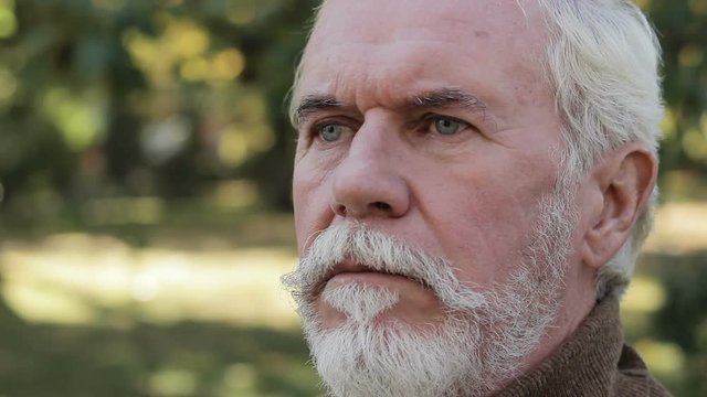 Portrait of frowning wrinkled senior man, staring ruefully, gloomily far away
