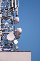 Telecommunication base stations network repeaters on the roof of building. The cellular communication aerial on city building roof. Cell phone telecommunication tower. Antennas on top of building.