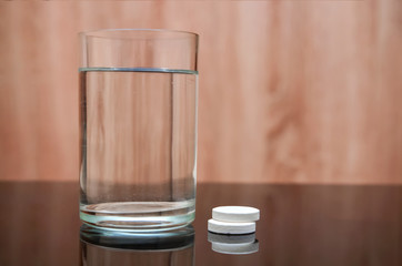 Anesthetic tablet, vitamins, in a glass of water with bubbles on a black table. Copy-space.