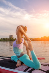 Fototapeta na wymiar Young beautiful woman meditating in a sea at SUP paddleboarding. Healthy lifestyle.