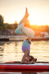 Sporty woman in yoga position on paddleboard, doing yoga on sup board, exercise for flexibility and...