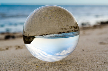 glass ball lens lies on the sand of the sea shore