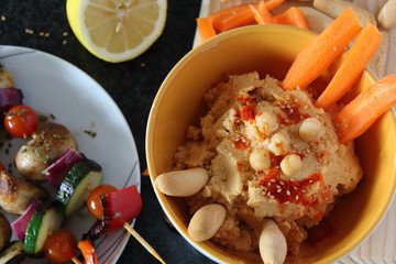 Hummus, fresh carrot sticks, bread and boiled chickpeas in bowl. Vegan food concept, dark background, top view.