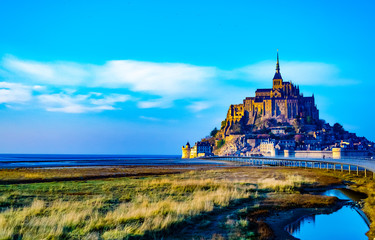 Medieval castle, against the blue sky and white clouds, the castle on the island, the castle is surrounded by water, green grass, a fortress and abbey, an incredibly beautiful castle like from a fairy