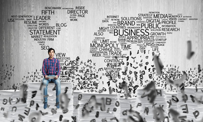Attractive man sitting on pile of paper documents.
