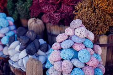 Multicolored pumice stones dry green and gray algae and colorful pink goods in wooden buckets and baskets for spa and bath hygiene at traditional arabian bazaar