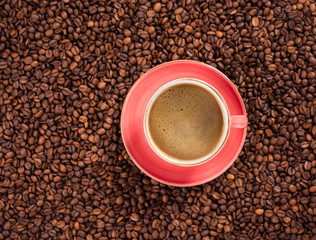 Pink coffee cup in filter coffee, coffee beans in background