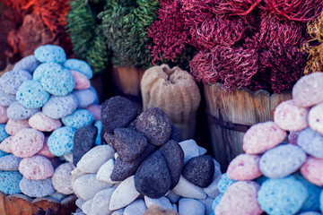 Multicolored pumice stones dry green and gray algae and colorful pink goods in wooden buckets and baskets for spa and bath hygiene at traditional arabian bazaar