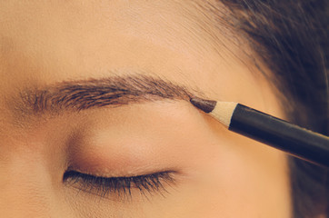 Beauty face of Asian woman by applying eyebrow pencil and smooth skin by cosmetics.