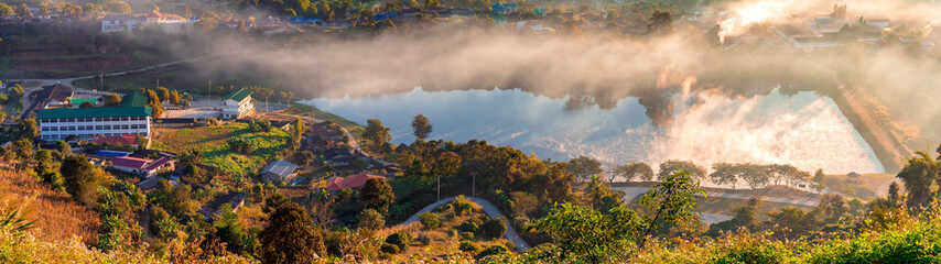 View of village and lake covered in foggy during morning sunrise.