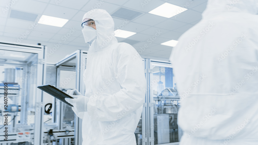 Poster quality control check: scientist using digital tablet computer and wearing protective suit walks thr