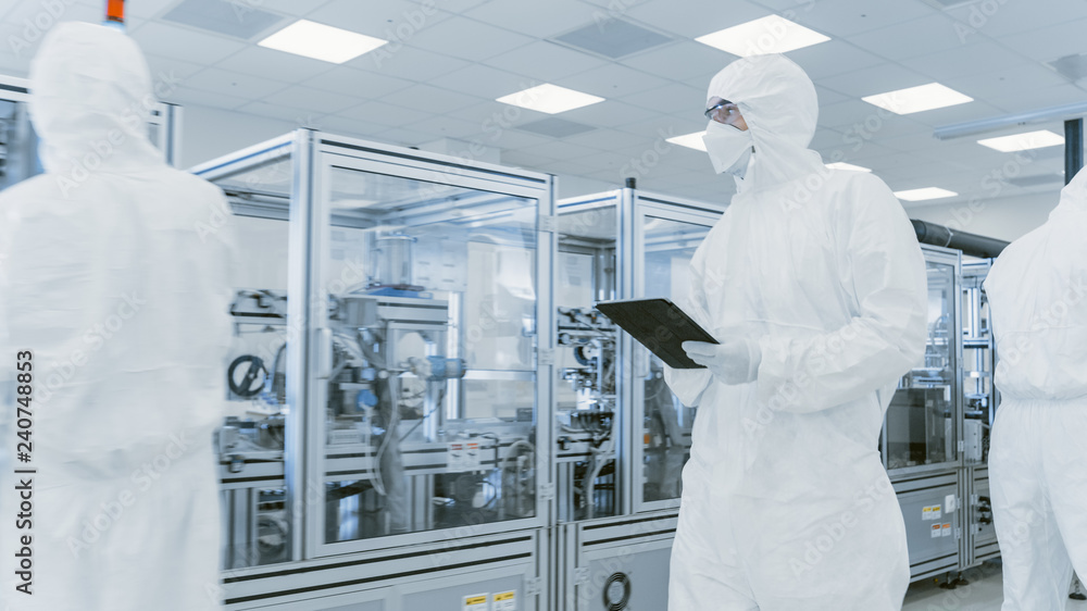 Poster quality control check: scientist using digital tablet computer and wearing protective suit walks thr