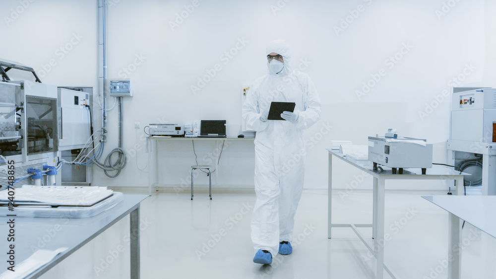 Poster quality control check: scientist using digital tablet computer and wearing protective suit walks thr