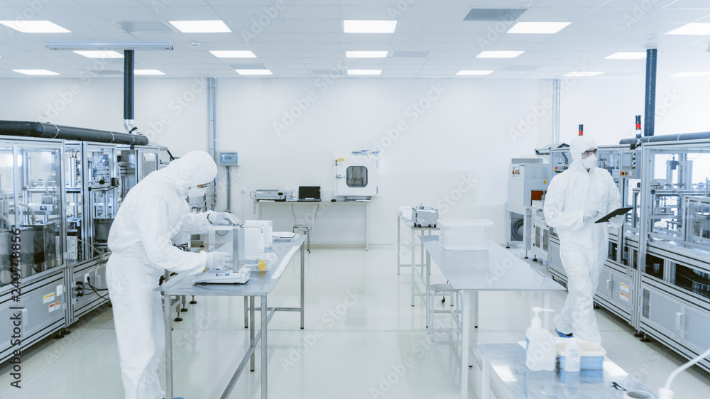 Poster quality control check: scientist using digital tablet computer and wearing protective suit walks thr