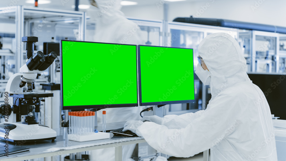 Poster in laboratory over the shoulder view of scientist in protective clothes working on personal computer