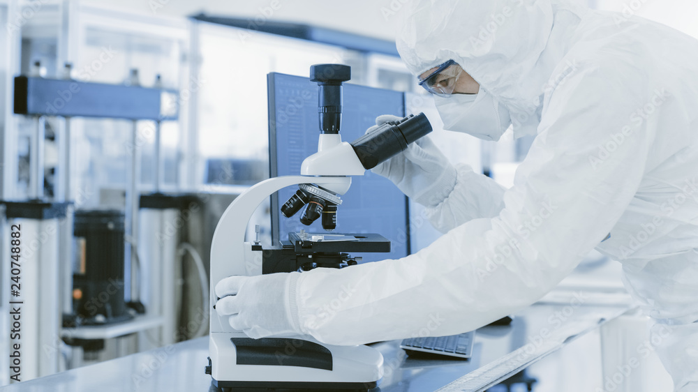 Poster in laboratory scientist in protective clothes doing research uses microscope and personal computer. 