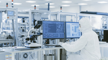 Fototapeta In Laboratory Over the Shoulder View of Scientist in Protective Clothes Doing Research on a Personal Computer. Modern Manufactory Producing Semiconductors and Pharmaceutical Items. obraz