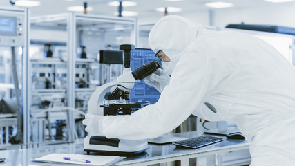 In Laboratory Scientist in Protective Clothes Doing Research Uses Microscope and Personal Computer....