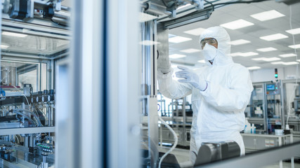 In the Manufacturing Facility Shot of Scientist in Sterile Protective Clothing Work on a Modern Industrial 3D Printing Machinery. Pharmaceutical, Biotechnological and Semiconductor Creating