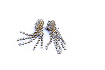 Close up gold and silver earrings isolated on white with some precious gems on it.