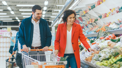At the Supermarket: Happy Young Couple Chooses Organic Vegetables in the Fresh Produce Section of...