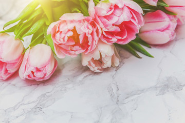 Spring greeting card. Bouquet of fresh light pastel pink tulips flowers on marble background. Happy holiday easter mother day anniversary valentine day birthday concept. Flat lay top view copy space