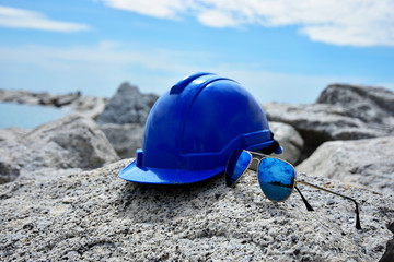 Safety Helmet and the sun glasses on the seascape background