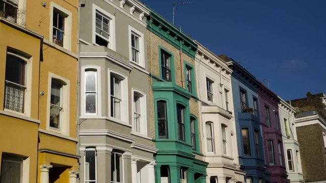 Vibrant row houses with multiple colors forming a london street scene under blue sky