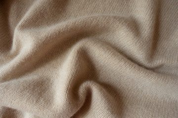 Fototapeta premium Cream colored knitted fabric in soft folds