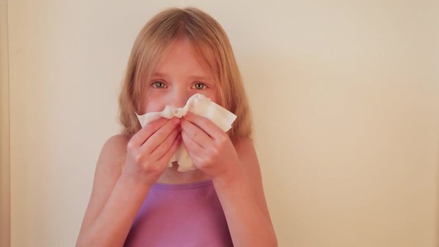 cute blond hair little girl blowing her nose with paper tissue. Child winter flu allergy health care concept